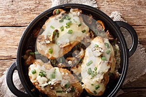 Baked chicken breast with mushrooms, green onions, mozzarella and parmesan close-up in a pan. Horizontal top view