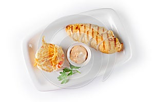 Baked chicken breast with sauce and rice with vegetables on a white rectangular plate on white background, top view