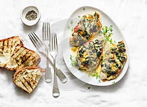 Baked chicken breast with tomatoes, spinach and mozzarella - delicious diet lunch in mediterranean style on a light background