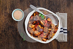 Baked chicken breast with vegetables and sauce on wooden table