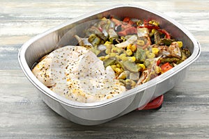 Baked chicken breasts with vegetables in cooking pan