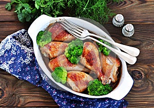 Baked chicken drumstick with organic broccoli on a wooden background.