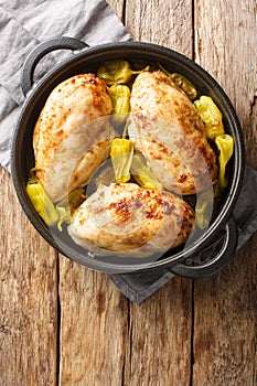Baked chicken fillet with pepperoncini pepper close-up in a frying pan. Vertical top view