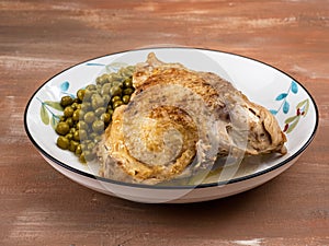 Baked chicken and green canned peas and on a plate with a pattern