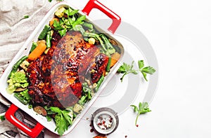 Baked chicken in honey glaze with garnish of vegetables, white background, top view