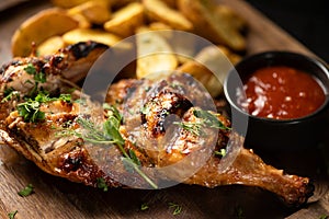 Baked chicken leg with fries potatoes on wooden board. Baking dish on table. Grilled chicken legs.