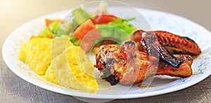 Baked chicken legs, Polenta or Mamaliga and salad in fancy plate. Traditional food and culinary culture specific for Balkan