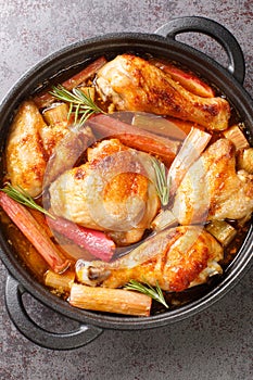 Baked chicken with rhubarb and white wine close-up in a frying pan. vertical top view