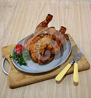 Baked whole chicken on white plate on wooden background. photo