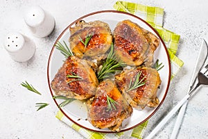 Baked chicken thighs with herbs on white plate.