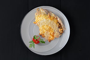 Baked chicken under cheese with tomate and parsley