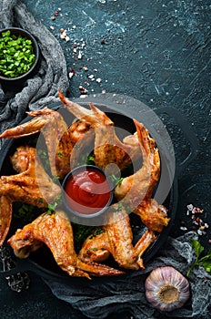 Baked chicken wings in a pan with ketchup and onions. Barbecue. Top view.