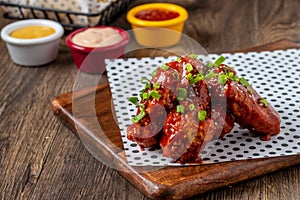 Baked chicken wings with sesame and sauce on wooden background