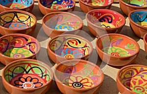 Baked clay pots decorated with colorful drawings on an open-air market stall