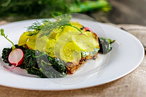 Baked cod with potatoes on a white plate partial blurring