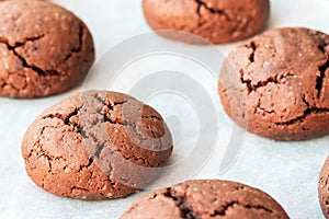 Baked cracked round chocolate cookies on a baking sheet with parchment paper just taken out of the oven. Tea snack