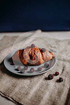 Baked croissant with berries on a gray plate on the kitchen table and sack cloth photo