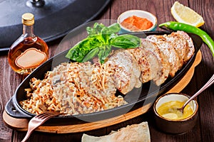 Baked dish of beef, noodles, rice, mushrooms, onions served with butter, spices and cognac in pan on wooden table