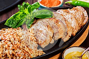 Baked dish of beef, noodles, rice, mushrooms, onions served with butter, spices and cognac in pan on wooden table