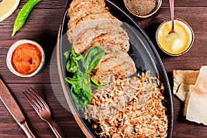 Baked dish of beef, noodles, rice, mushrooms, onions served with butter, spices and cognac in pan on wooden table