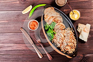 Baked dish of beef, noodles, rice, mushrooms, onions served with butter, spices and cognac in pan on wooden table.