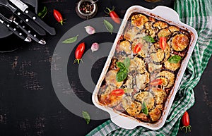 Baked eggplant with cheese on a dark wooden table. Parmigiana melanzane. Top view. Italian cuisine. Copy space photo