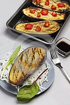 Baked eggplant with greens and rice noodles on plate