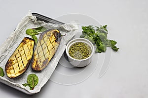 Baked eggplant halves in pallet. Parsley leaves and mung bean in bowl