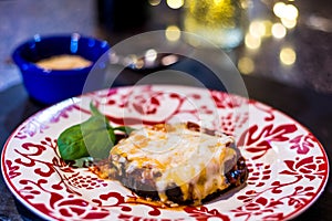 Baked Eggplant Parmagiana on red and white plate, gluten free - no egg or breadcrumbs.