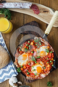 Baked eggs with sausage and vegetables in the pan. close up top view