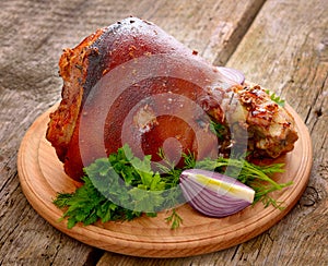 Baked Eisbein with wegetables on wooden board