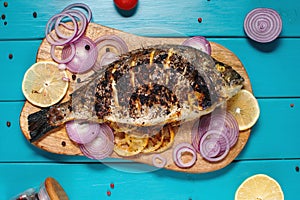 Baked fish dorado. Sea bream or dorada fish grilled on a blue wooden background. top view