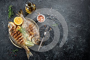 Baked fish dorado. Sea bream or dorada fish grilled on a dark background. top view