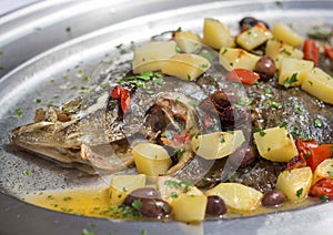 Baked flounder fish with potatoes, olives and tomates