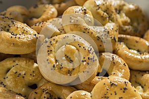 Baked fresh pretzels on wooden table, heart and twisted knot shapes, covered with poppy seeds salt and caraway seeds