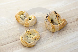 Baked fresh pretzels on wooden table, heart and twisted knot shapes, covered with poppy seeds salt and caraway seeds