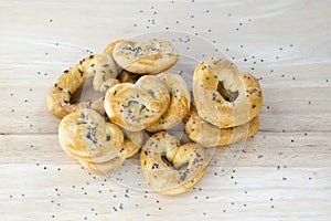 Baked fresh pretzels on wooden table, heart and twisted knot shapes, covered with poppy seeds salt and caraway seeds