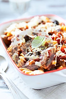 Baked fusilli pasta with cherry tomatoes, olives and mozzarella cheese. Bright wooden background.