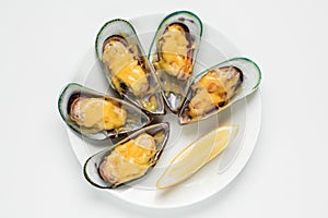 Baked green mussels appertizer with parmesan and garlic served with lemon top view on a white plate