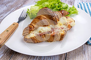 Baked ham croissant in a plate with salad