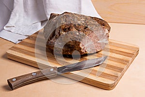 Baked ham with herbs and spice on wooden board.