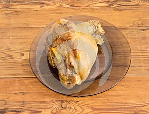 Baked ham hock on glass dish on wooden surface