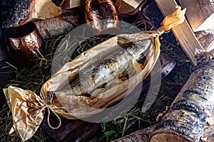 baked mackerel in a paper bag on a background of firewood