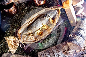 Baked mackerel in a paper bag on a wooden background