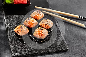 Baked Maki sushi on dark slate. Hot unagi maki with tobiko. Sushi roll with baked cheese, masago and unagi sauce topped. Style