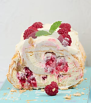 Baked meringue roll with cream and fresh red raspberry, white background