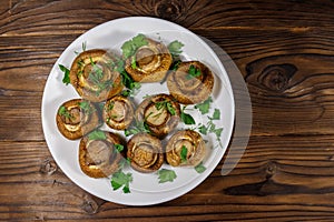 Baked mushrooms in plate on wooden table. Top view