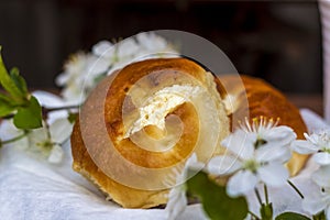 Baked open rolls and a cup of coffee on a dark, worn rustic wooden table. The composition is decorated with a twig with white