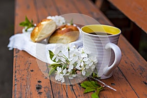 Baked open rolls and a cup of coffee on a dark, worn rustic wooden table. The composition is decorated with a twig with white
