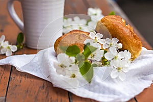 Baked open rolls and a cup of coffee on a dark, worn rustic wooden table. The composition is decorated with a twig with white